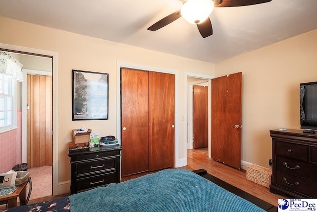 bedroom with a closet, wood finished floors, a ceiling fan, and baseboards