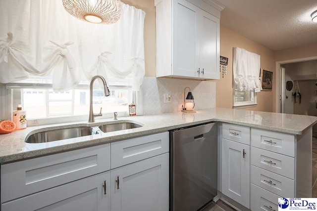 kitchen with a peninsula, a sink, white cabinets, stainless steel dishwasher, and decorative backsplash