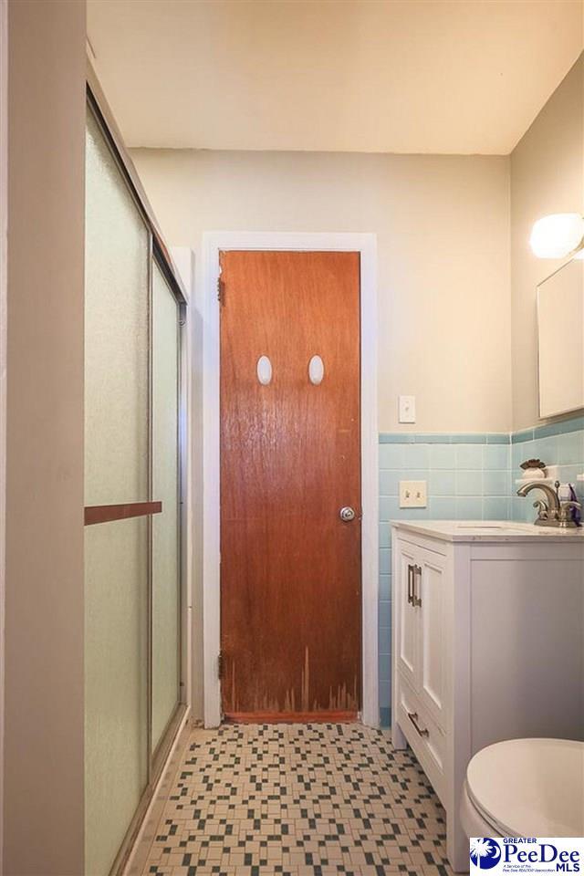 bathroom featuring a stall shower, vanity, tile walls, and tile patterned floors