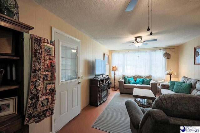 living area with a textured ceiling, carpet flooring, and a ceiling fan