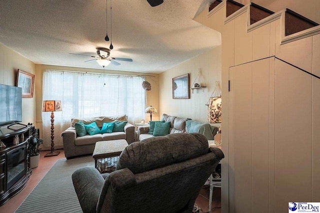 living area with ceiling fan and a textured ceiling