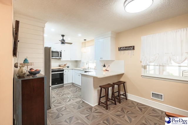 kitchen featuring stainless steel appliances, a wealth of natural light, visible vents, and a peninsula