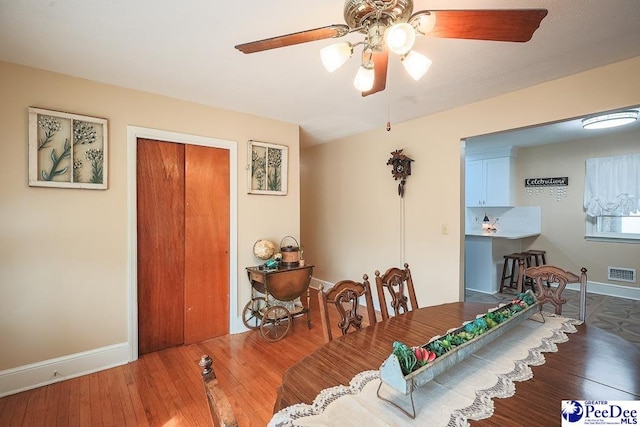 dining space featuring hardwood / wood-style floors, a ceiling fan, visible vents, and baseboards