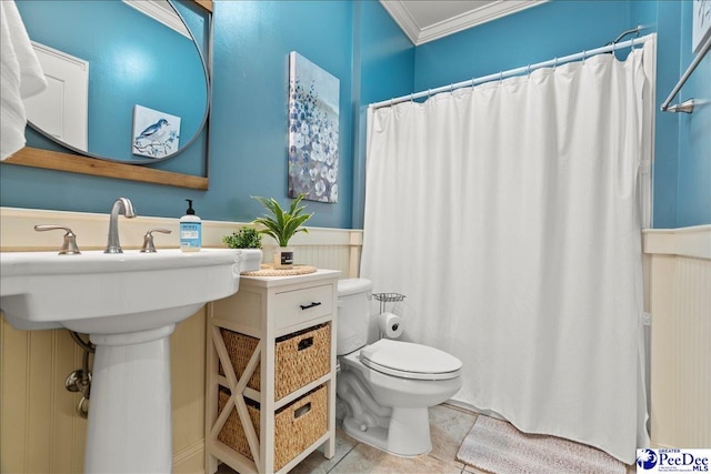 bathroom with a shower with shower curtain, a wainscoted wall, ornamental molding, tile patterned flooring, and toilet