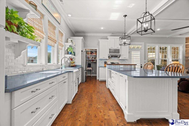 kitchen with white cabinetry, dark countertops, crown molding, and a center island