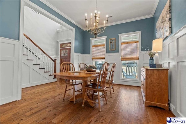 dining room featuring stairs, crown molding, wood-type flooring, and a chandelier