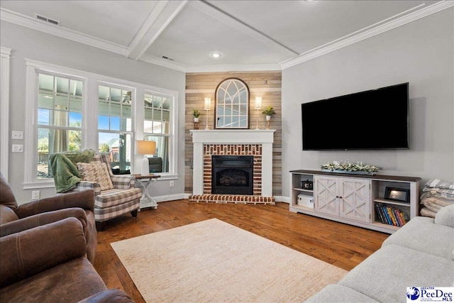 living area featuring visible vents, a fireplace, crown molding, and wood finished floors