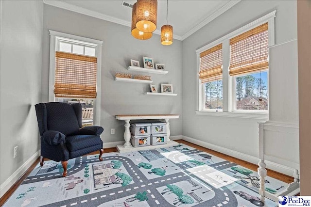 living area with visible vents, baseboards, wood finished floors, and crown molding