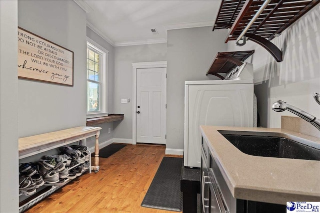 washroom featuring baseboards, ornamental molding, laundry area, wood finished floors, and washer / clothes dryer