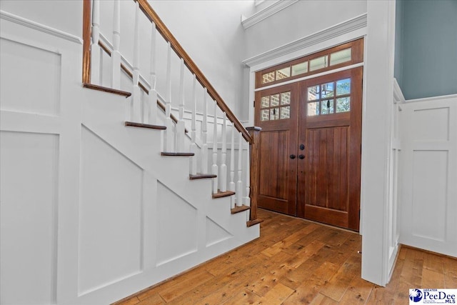 foyer entrance with a decorative wall, stairs, and light wood finished floors