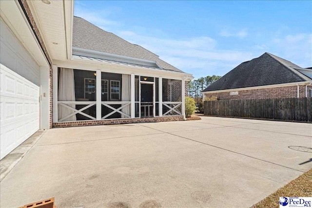 view of patio / terrace featuring fence, driveway, and a sunroom