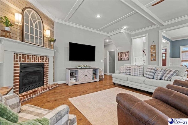 living room with wood finished floors, baseboards, recessed lighting, ornamental molding, and a brick fireplace