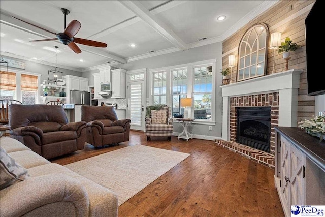 living room with a brick fireplace, dark wood-type flooring, crown molding, beam ceiling, and coffered ceiling