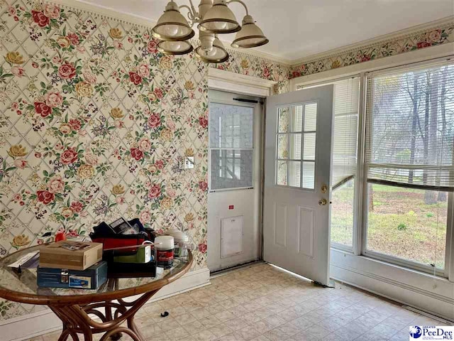 doorway to outside featuring wallpapered walls, crown molding, a notable chandelier, and light floors