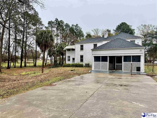 view of front facade featuring driveway, a sunroom, and roof with shingles