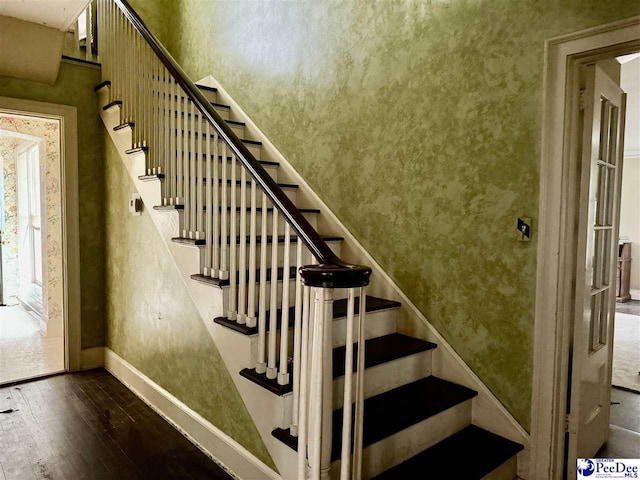 stairs with wallpapered walls, hardwood / wood-style flooring, and baseboards