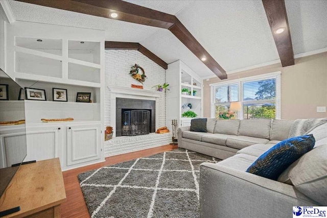 living room with vaulted ceiling with beams, a textured ceiling, built in shelves, a fireplace, and wood finished floors