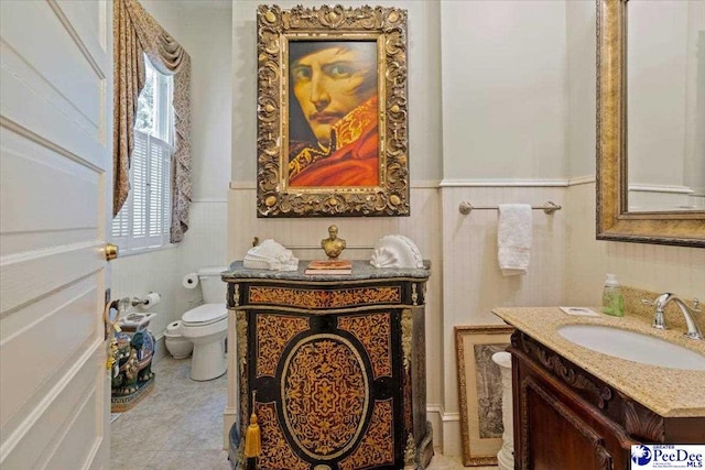 half bathroom with a wainscoted wall, vanity, and toilet
