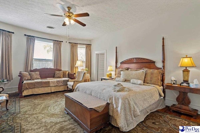 bedroom with wood finished floors, a ceiling fan, a textured ceiling, and visible vents
