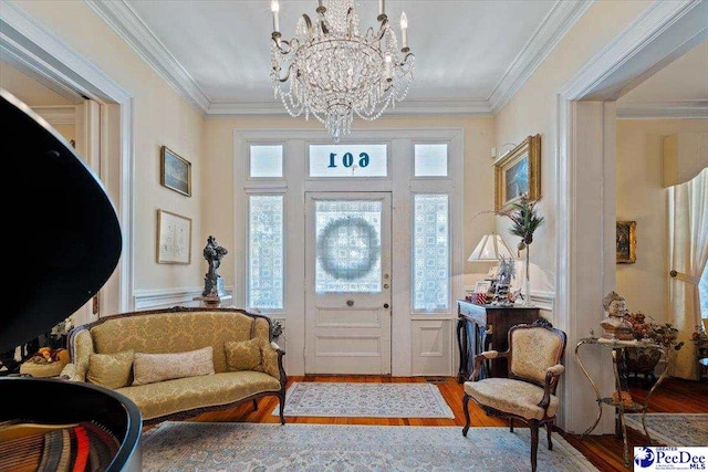 foyer entrance featuring a wainscoted wall, ornamental molding, wood finished floors, and a chandelier
