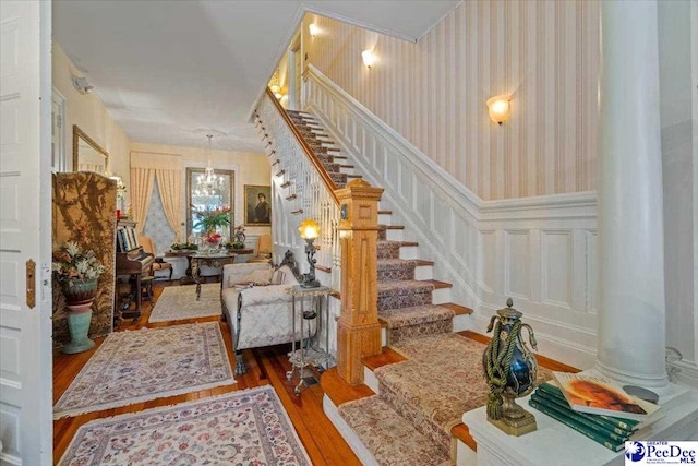 foyer featuring wainscoting, stairs, wood finished floors, a decorative wall, and wallpapered walls