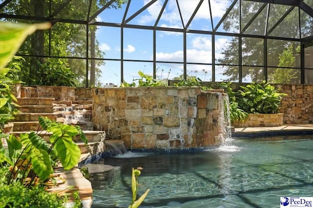 view of pool with pool water feature and glass enclosure