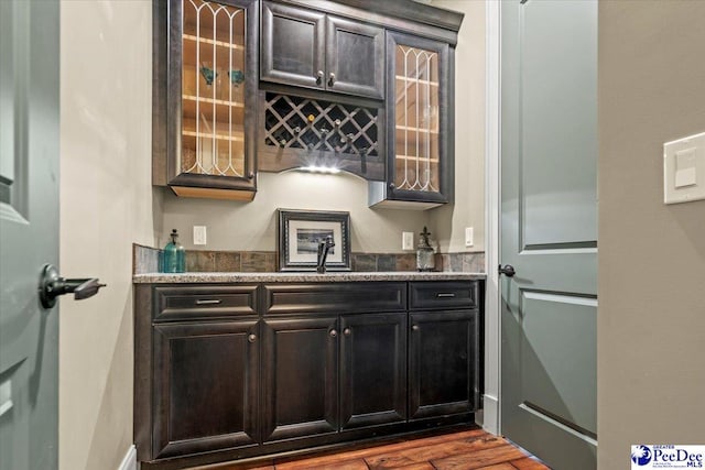 bar with dark stone countertops, sink, and hardwood / wood-style floors