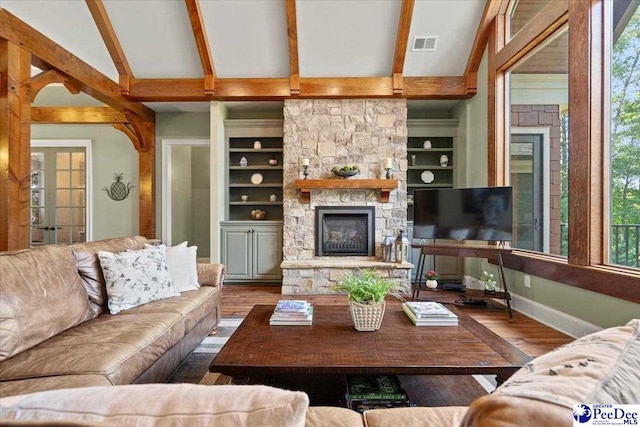 living room featuring wood-type flooring, vaulted ceiling with beams, built in features, and a fireplace