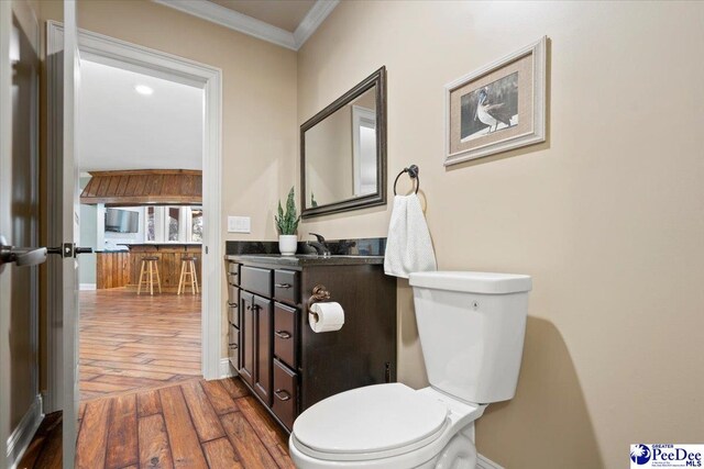 bathroom with ornamental molding, toilet, hardwood / wood-style floors, and vanity