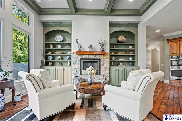 sitting room with dark hardwood / wood-style flooring, a stone fireplace, built in features, and beamed ceiling