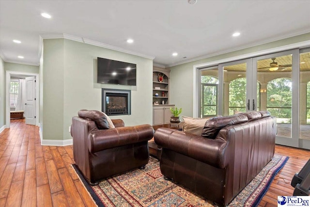 living room with french doors, ornamental molding, and light wood-type flooring