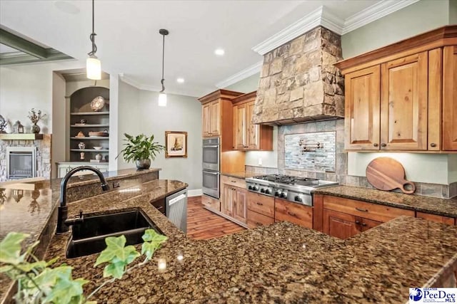 kitchen featuring dark stone countertops, sink, decorative light fixtures, and stainless steel appliances