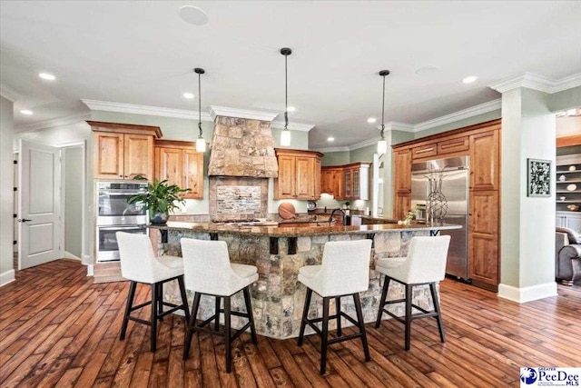 kitchen featuring stainless steel appliances, a large island, a breakfast bar, and custom range hood