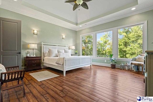 bedroom with a raised ceiling, wood-type flooring, and ornamental molding