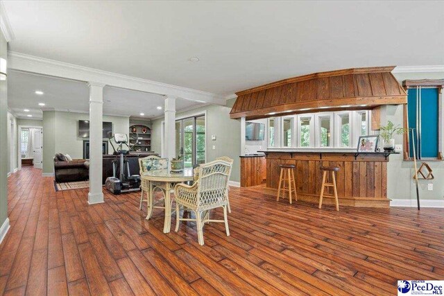 dining space featuring ornate columns, ornamental molding, and dark hardwood / wood-style flooring