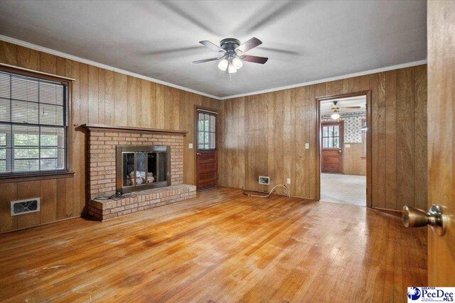 1817 E Sandhurst Dr, Florence, SC 29505 - unfurnished living room featuring ceiling fan, wood finished floors, wooden walls, a fireplace, and crown molding