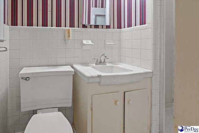1817 E Sandhurst Dr, Florence, SC 29505 - bathroom featuring toilet, wallpapered walls, tile walls, vanity, and a wainscoted wall