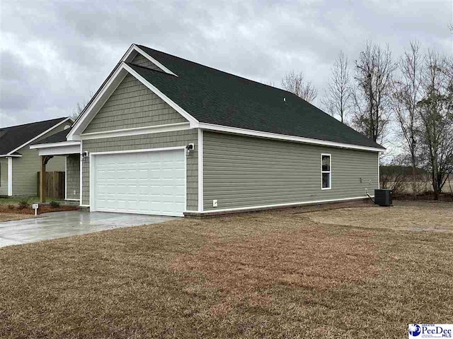 view of side of property featuring cooling unit, a garage, and a yard