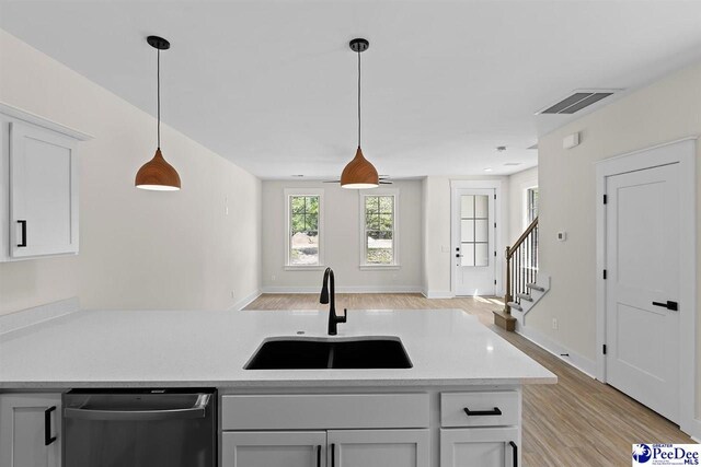 319 Railroad Ave, Florence, SC 29506 - kitchen featuring stainless steel dishwasher, a sink, light wood-type flooring, and pendant lighting