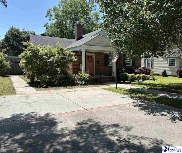 916 Kalmia St, Florence, SC 29501 - view of front of home with a chimney, covered porch, fence, and brick siding