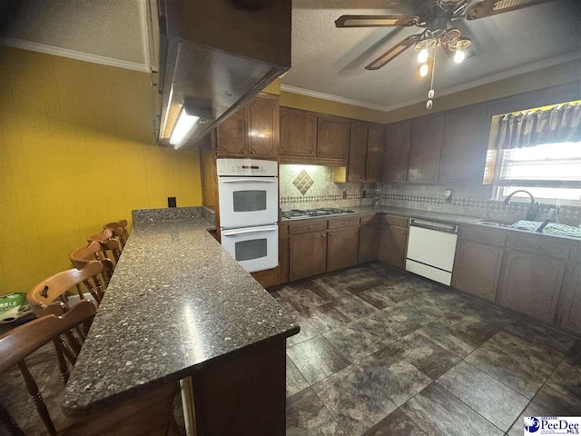 kitchen featuring white appliances, sink, decorative backsplash, and dark stone countertops