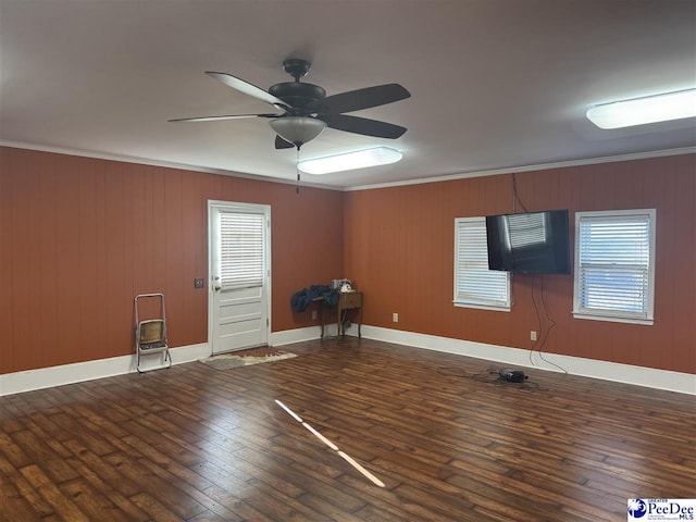 empty room with crown molding, dark wood-type flooring, and ceiling fan