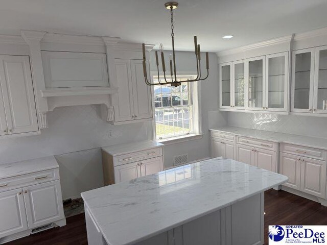 kitchen with dark wood-type flooring, pendant lighting, white cabinets, and light stone counters