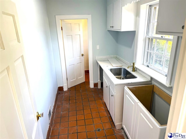 kitchen featuring dark tile patterned floors, white cabinetry, and sink