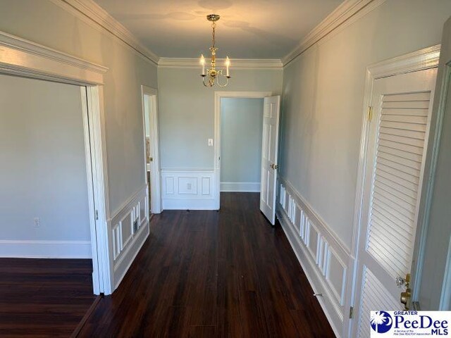 hallway featuring dark hardwood / wood-style flooring, crown molding, and a chandelier