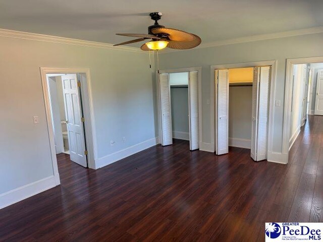 unfurnished bedroom featuring multiple closets, ornamental molding, and dark hardwood / wood-style floors