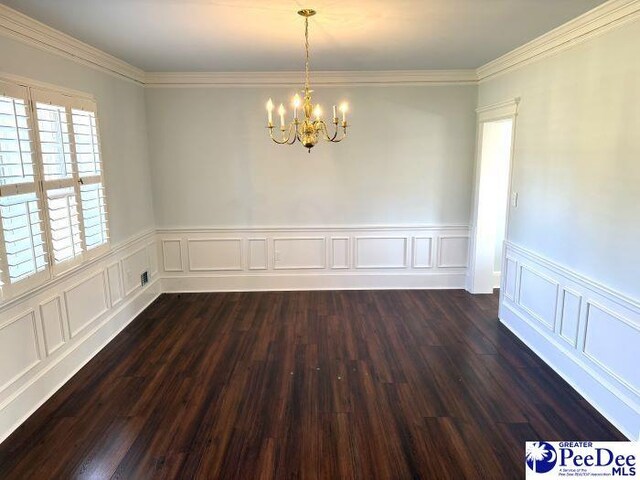 empty room with crown molding, dark hardwood / wood-style floors, and a notable chandelier