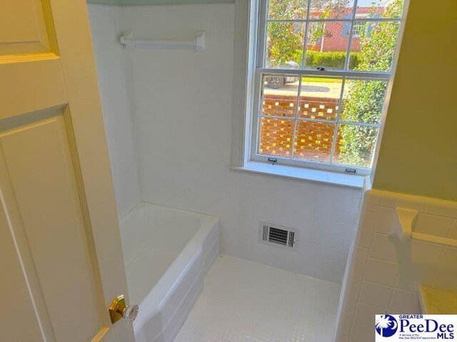 bathroom featuring a bathtub and tile walls