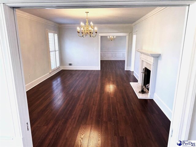 unfurnished living room featuring an inviting chandelier, ornamental molding, and dark hardwood / wood-style floors