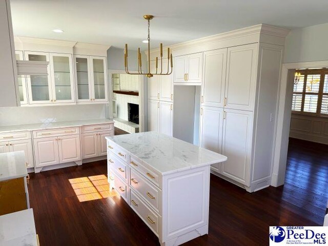 615 E Main St, Lake City, SC 29560 - kitchen with dark wood-type flooring, white cabinetry, hanging light fixtures, a center island, and light stone countertops